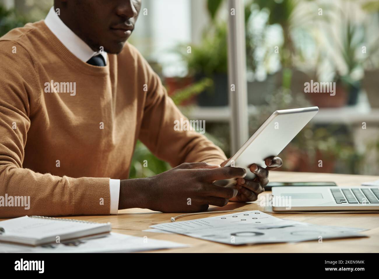 African American businessman using digital tablet for online work while sitting at his workplace at office Stock Photo