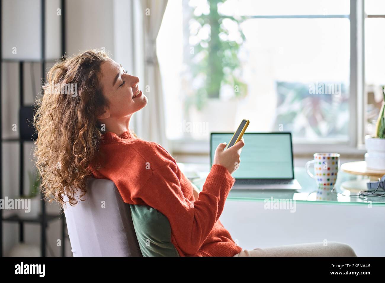 Young woman using phone relaxing taking break from remote work at home. Stock Photo