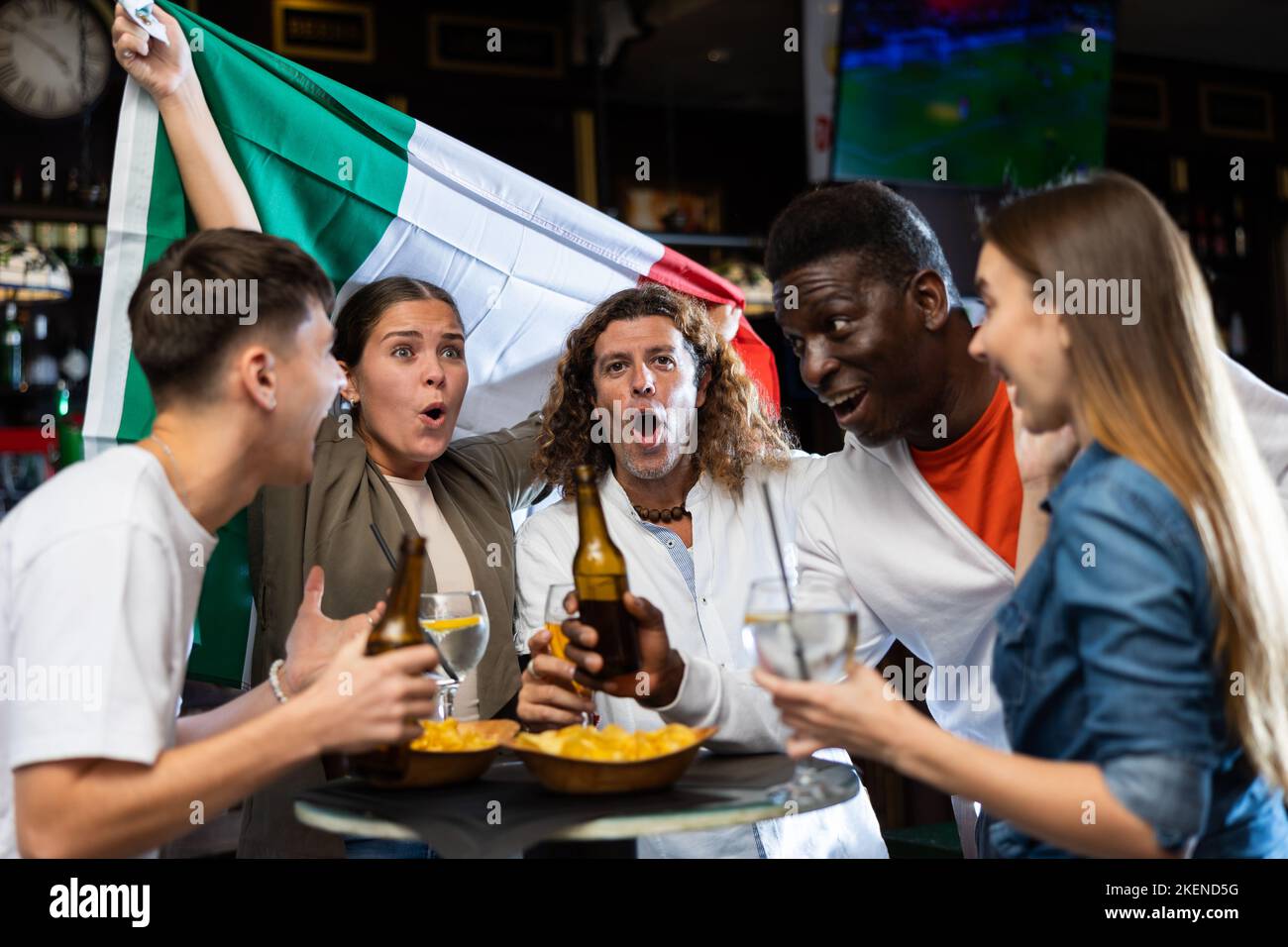 Happy multiracial people holding the flag of Italy and drinking beer in