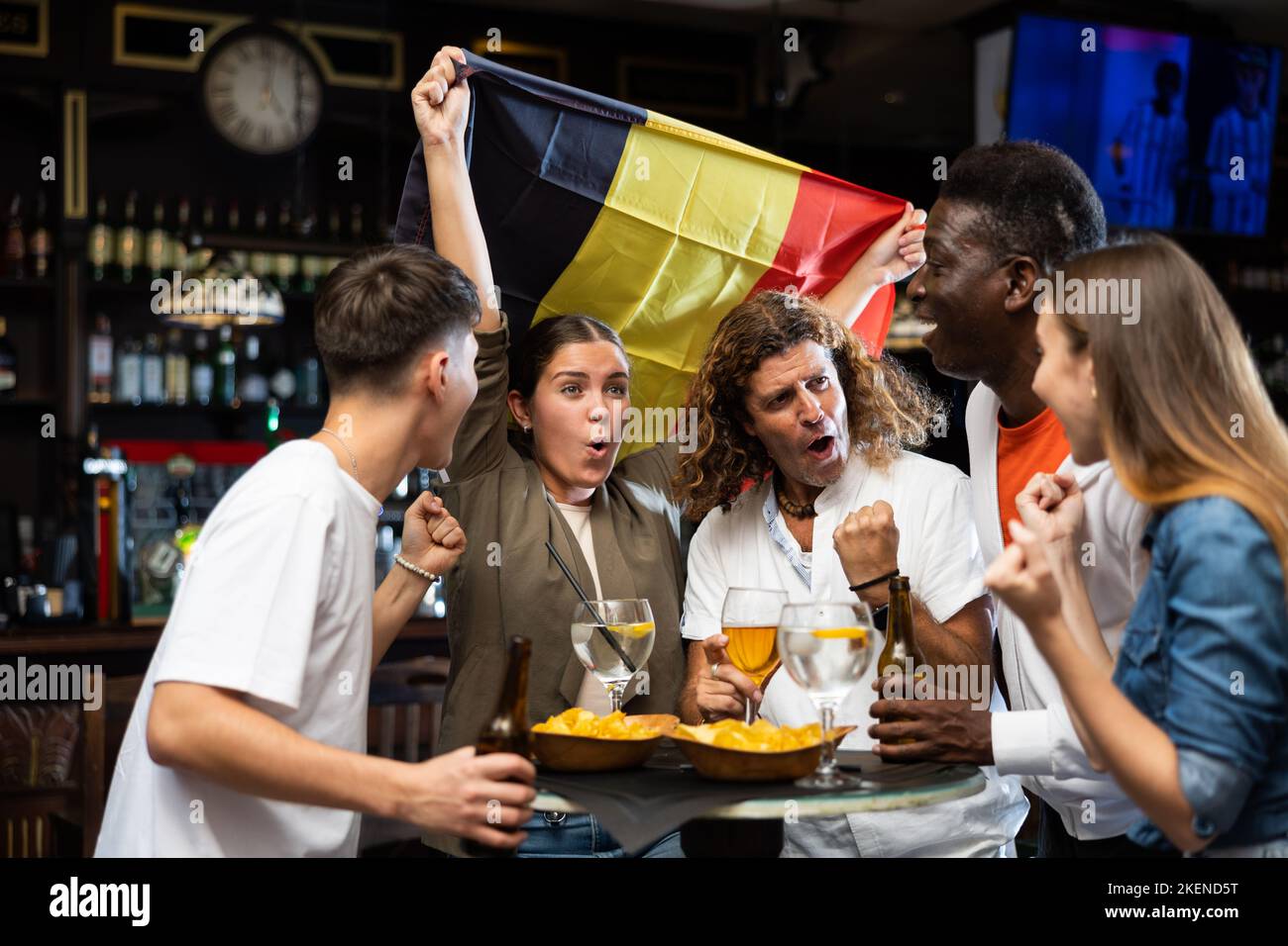Emotional multiracial sport supporters waving flag of Belgium while