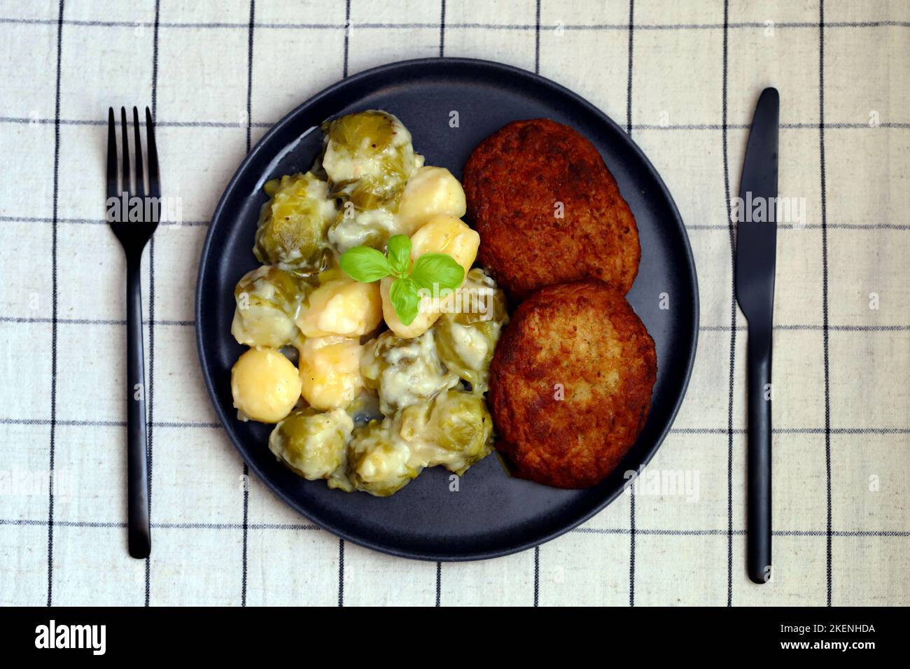 Schnitzels with potatoes and Brussels sprouts in white sauce. A dish of German cuisine. Stock Photo