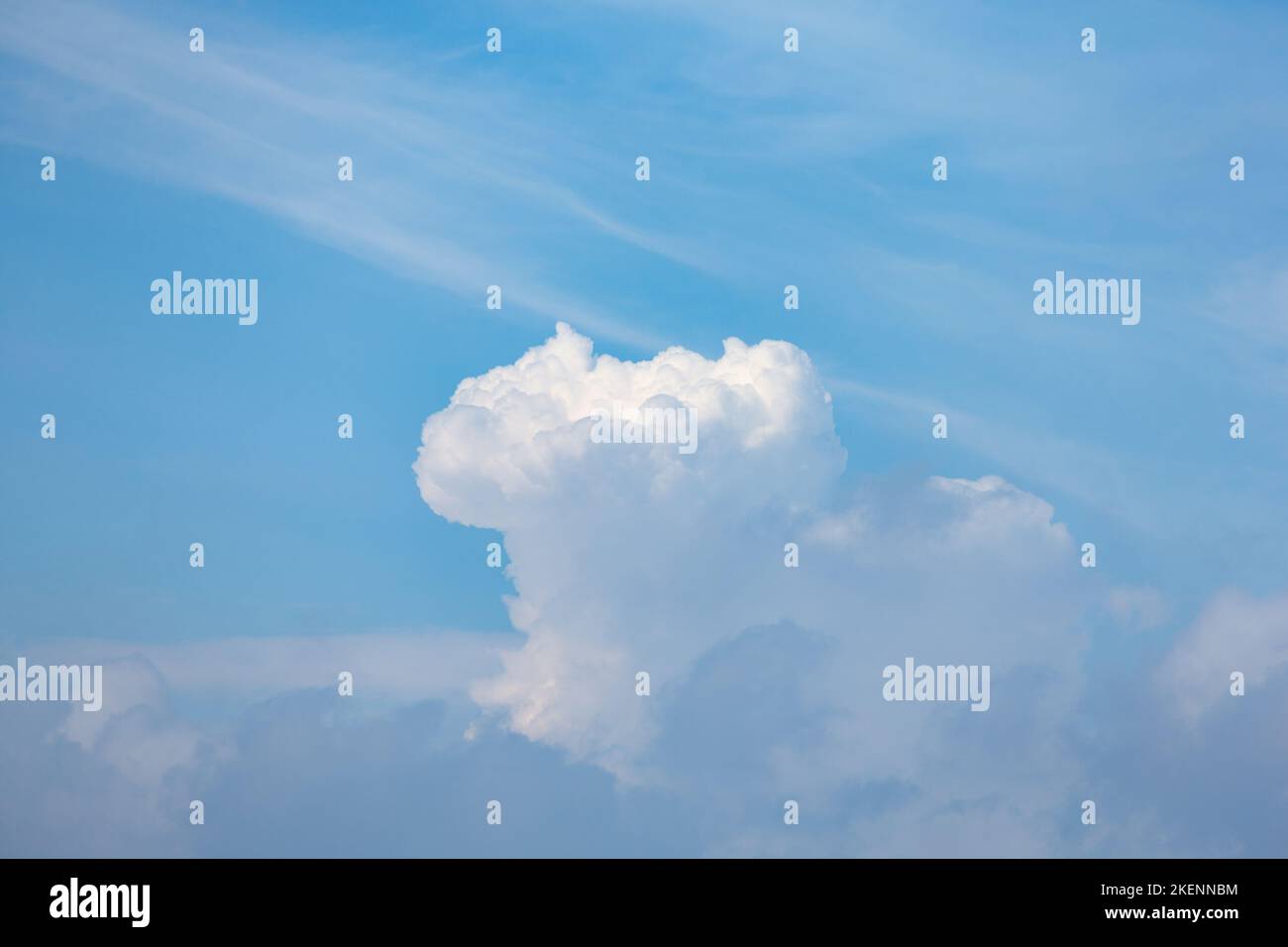 Mushroom shaped cloud form rises into a delicate blue sky Stock Photo