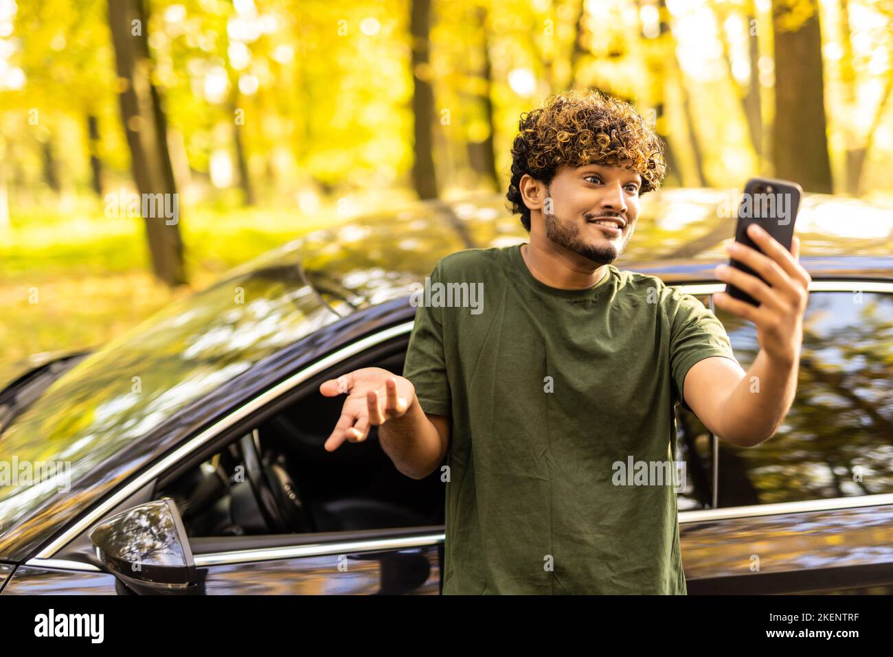 Indian man standing near his car and make video call on the phone Stock Photo