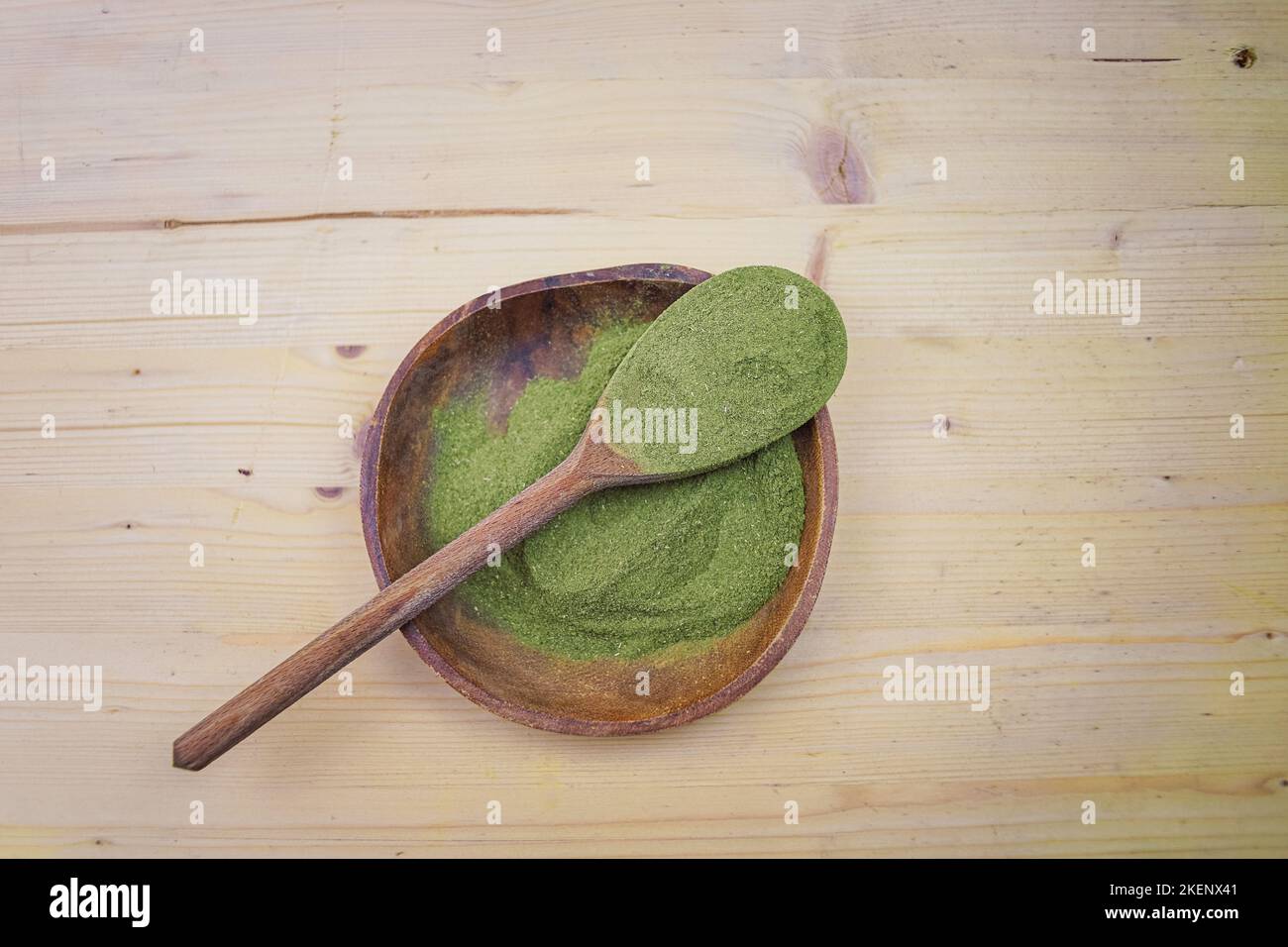 Top view of Kratom powder in wooden bowl and spoon on wooden table, alternative medicine Stock Photo