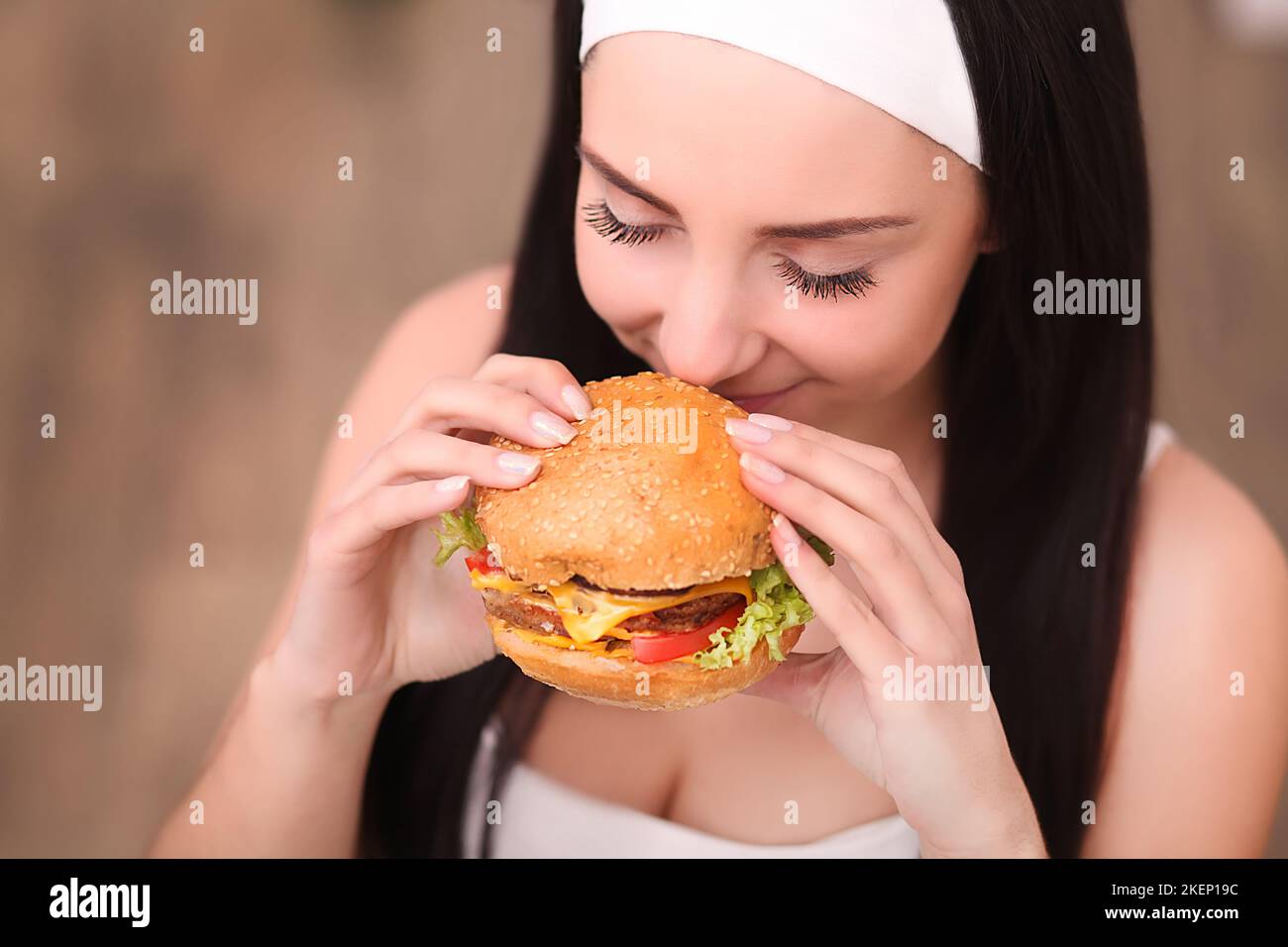 Young woman in a fine dining restaurant eat a hamburger, she behaves improperly Stock Photo