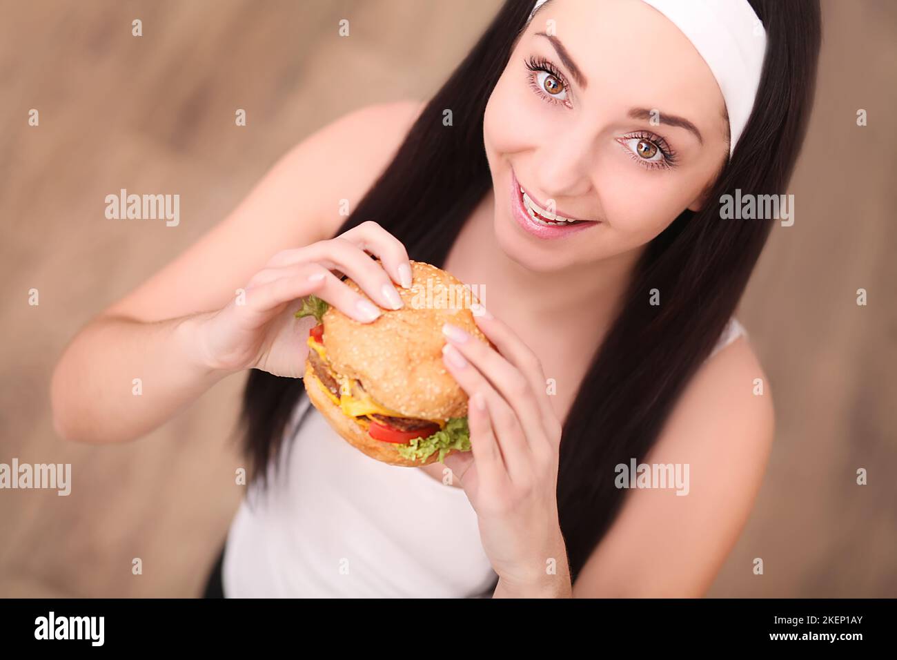 Young woman in a fine dining restaurant eat a hamburger, she behaves improperly Stock Photo