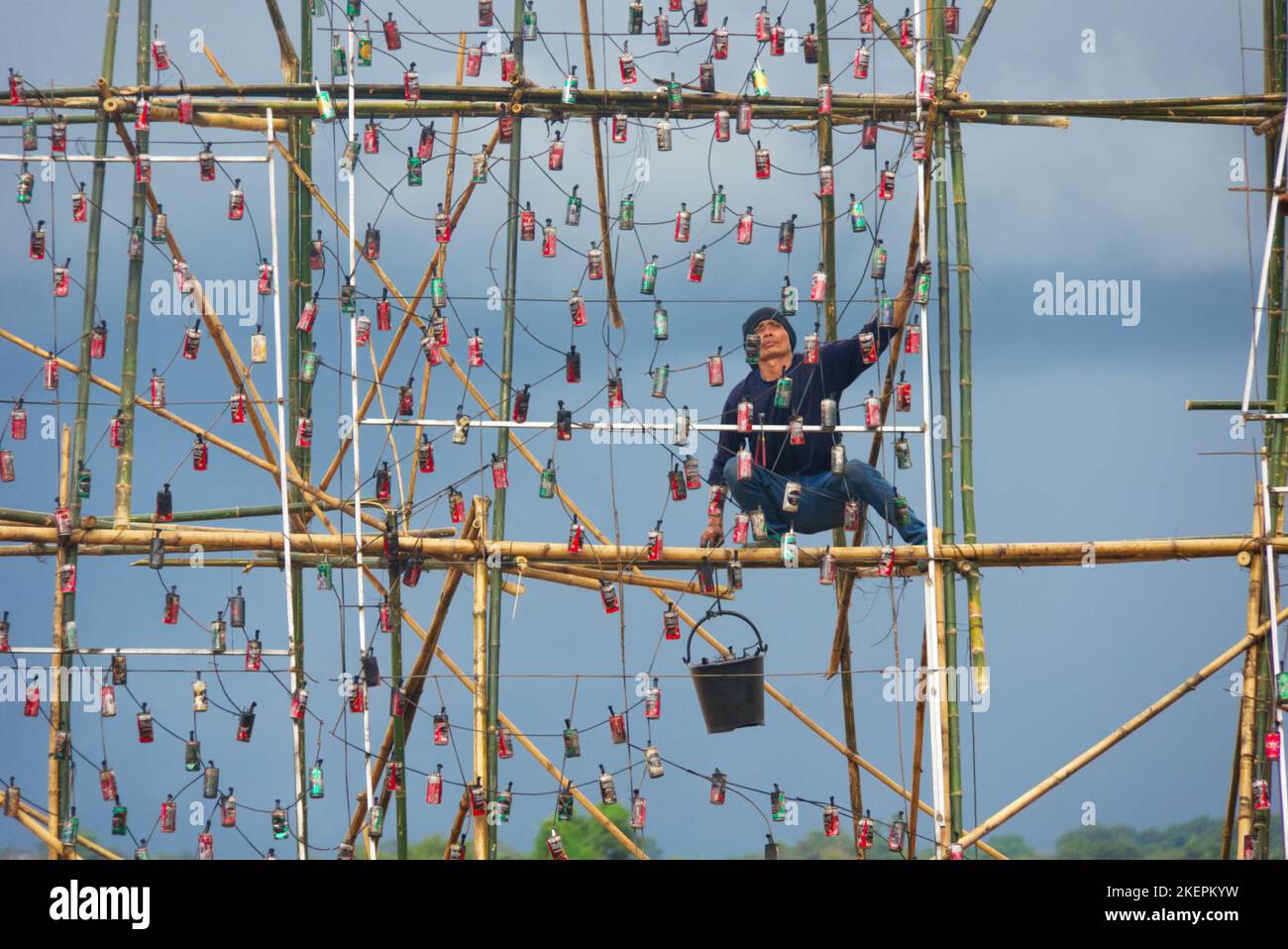 Asian man at work on bamboo scaffold preparing for Nakhon Phanom boat festival, Thailand. Stock Photo