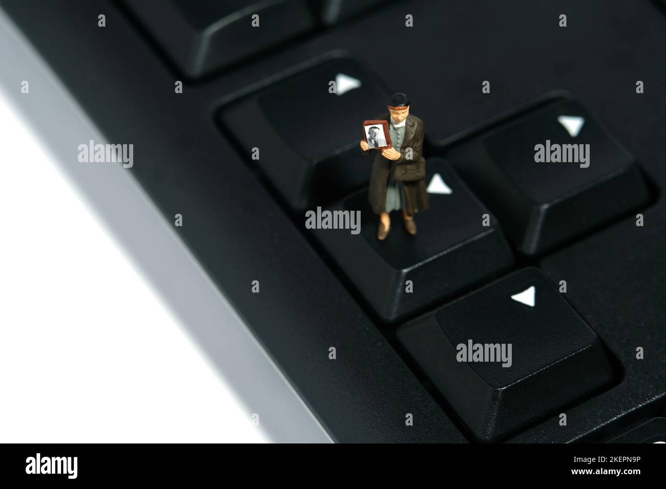 Miniature people toy figure photography. A woman holding photo frame standing above keyboard arrow, searching missing person because of war conflict. Stock Photo