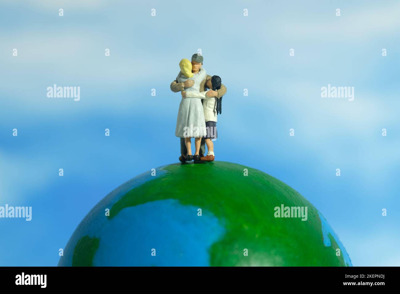 Miniature people toy figure photography. Family reunion day concept. Father hugging his wife and daughter above earth globe. Image photo Stock Photo