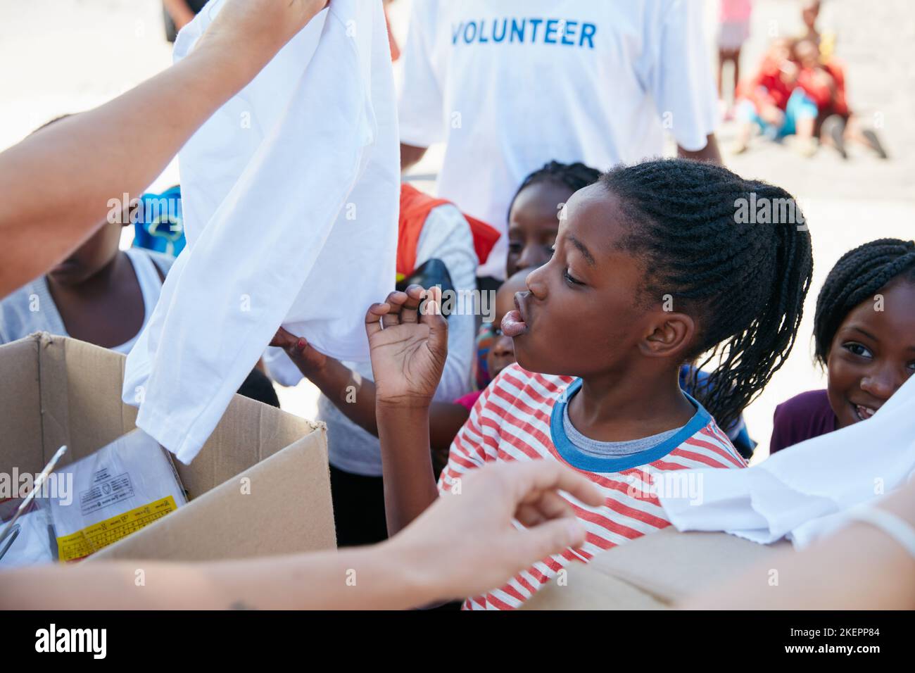 Excited to see all her new clothes. volunteer workers handing out clothing to underprivileged children. Stock Photo