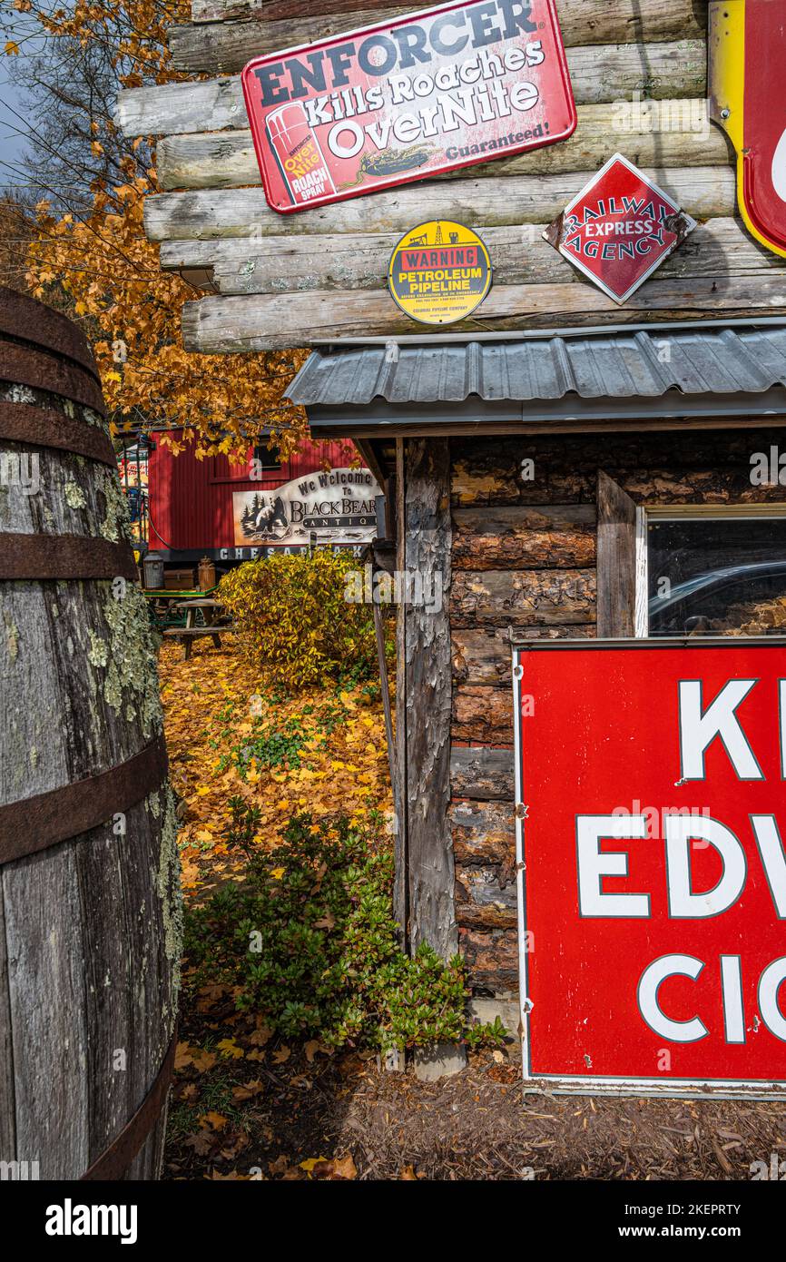 Vintage tin advertising signs on a log building in front of red caboose lodging at Black Bear Creek Antiques near Lake Burton in Clayton, Georgia. Stock Photo