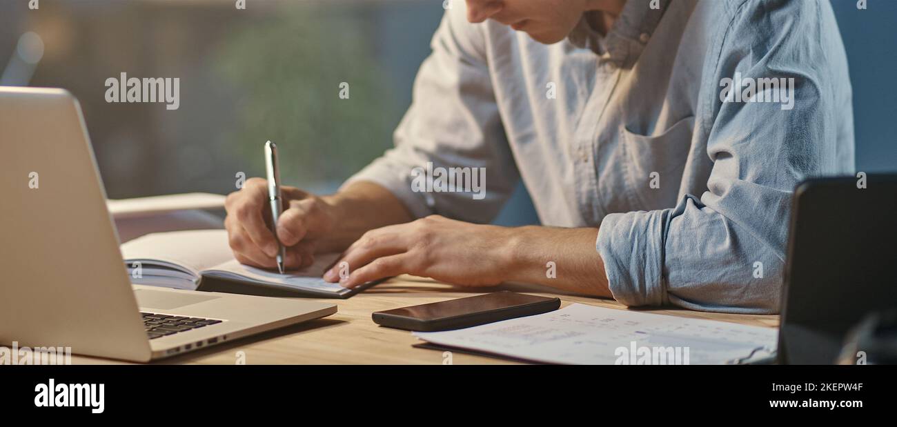 young entrepreneur taking notes in working at night. Stock Photo