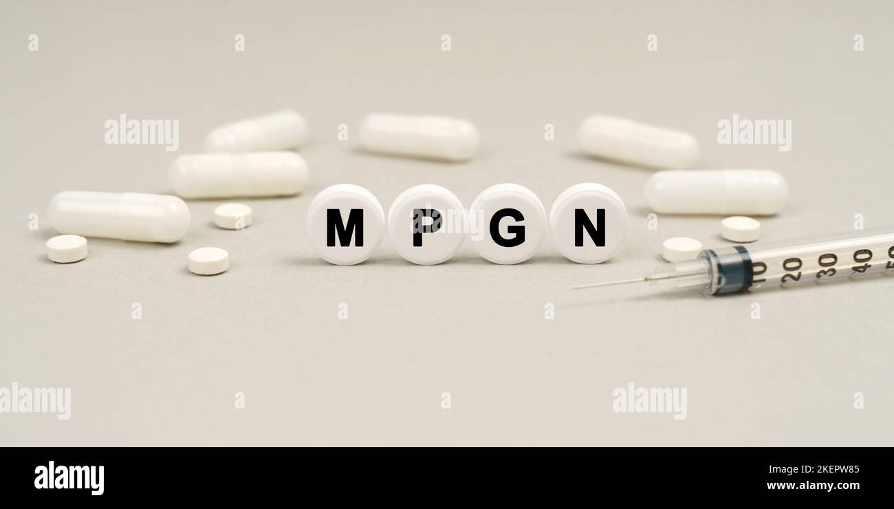 Medicine concept. On the table are capsules, a syringe and pills that say - MPGN Stock Photo