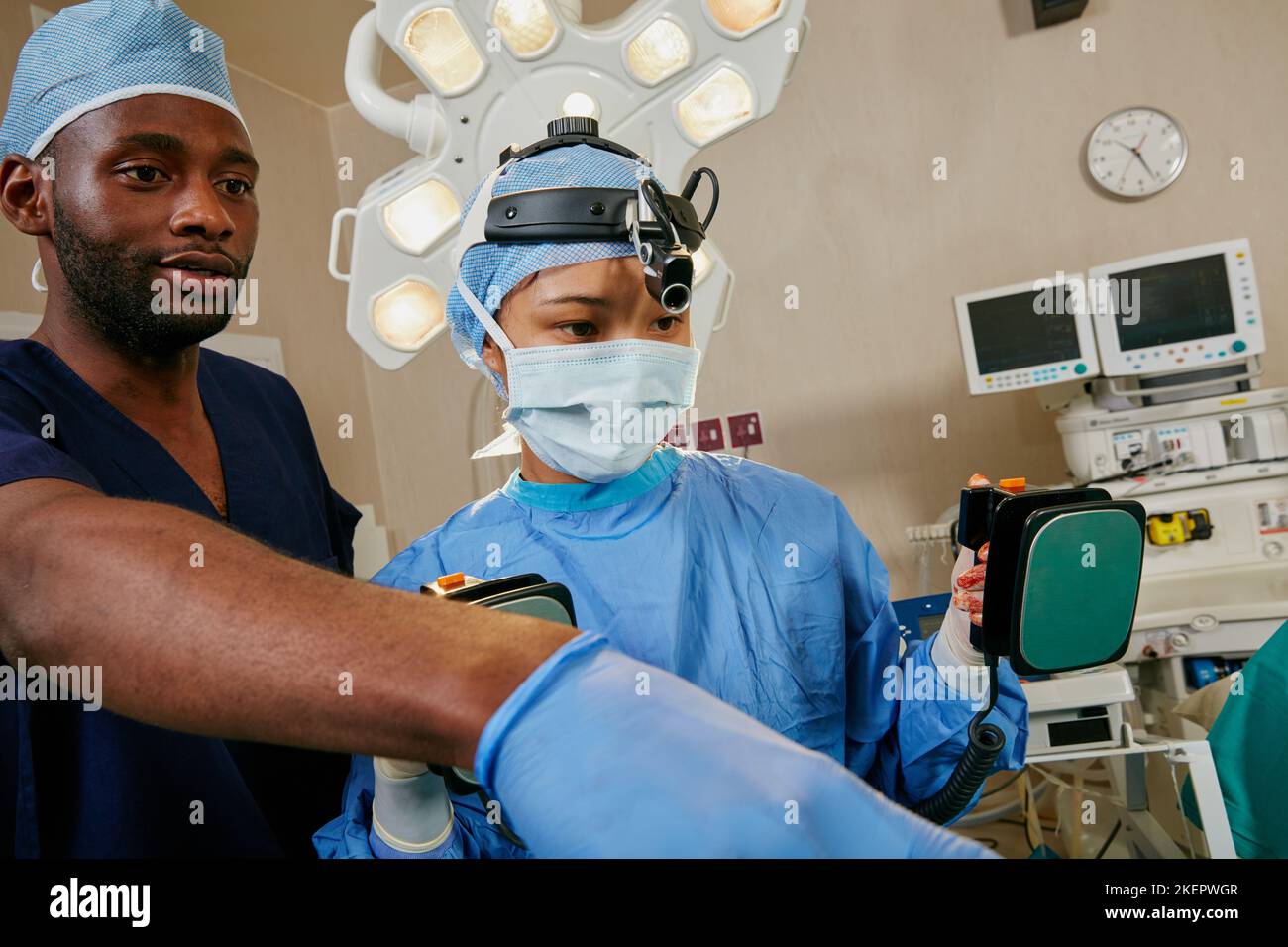 The patient is going into defib. a surgeon using a defibrillator on a