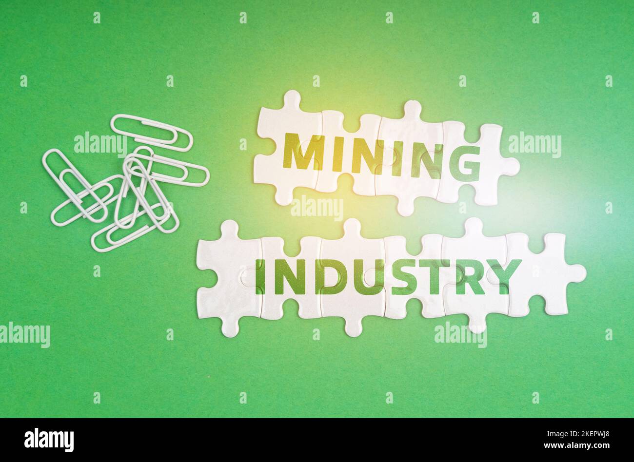 Ecology concept. On a green background, paper clips and white puzzles with the inscription - Mining Industry Stock Photo