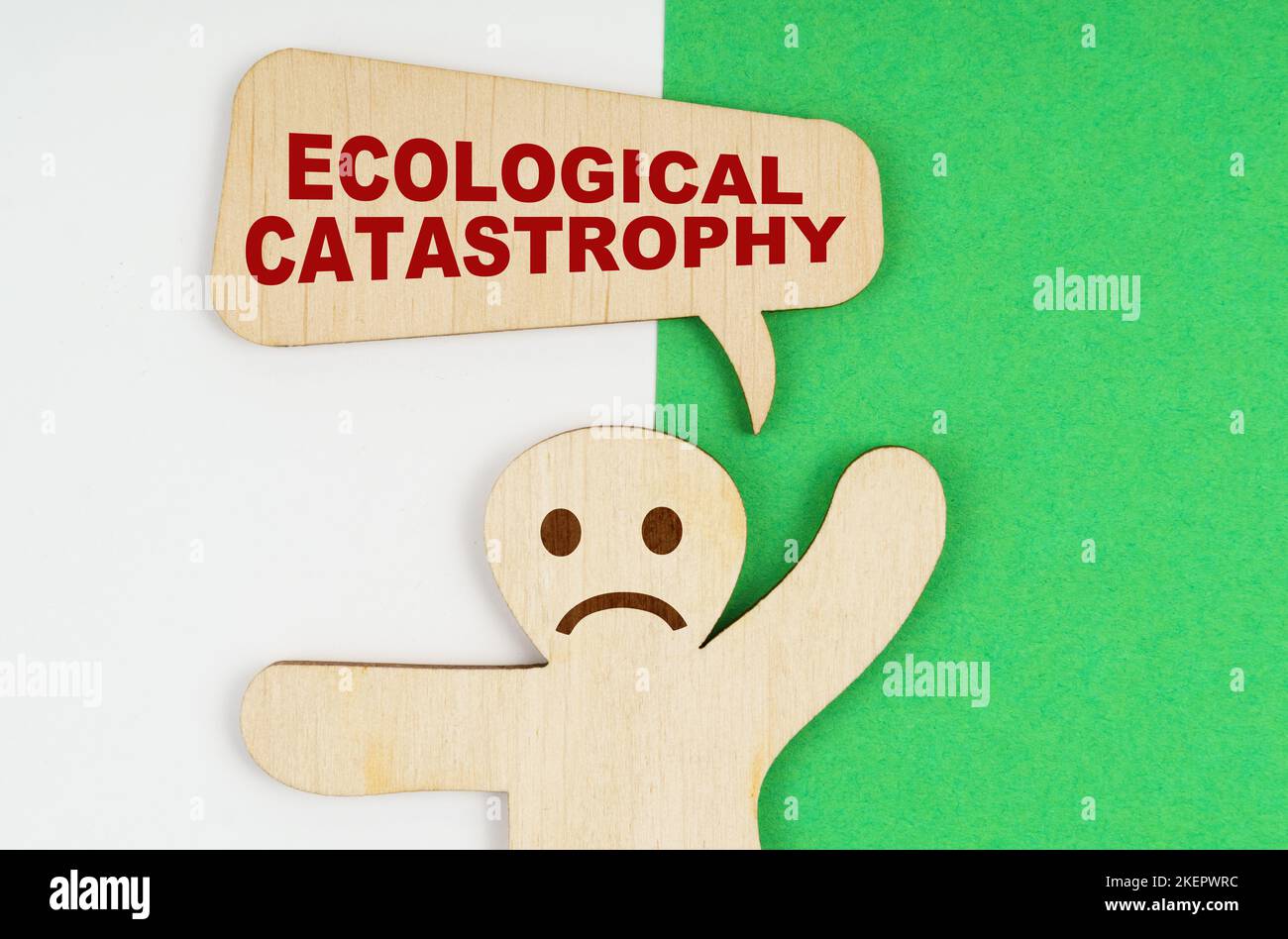 Environmental concept. On a green and white background, a sad wooden figure of a man and a plate with the inscription - Ecological catastrophy Stock Photo
