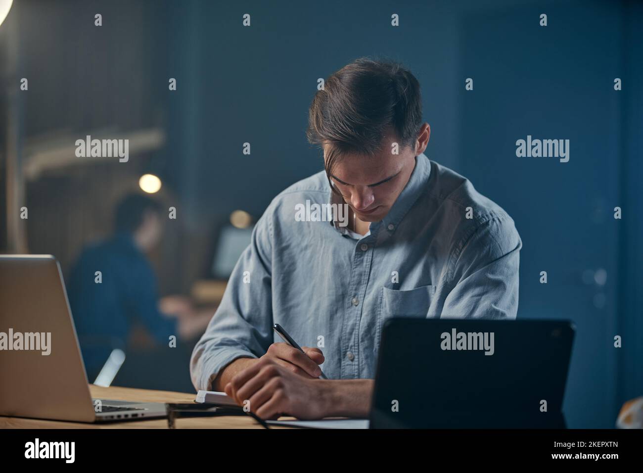 serious young entrepreneur writing something down in his weekly . Stock Photo