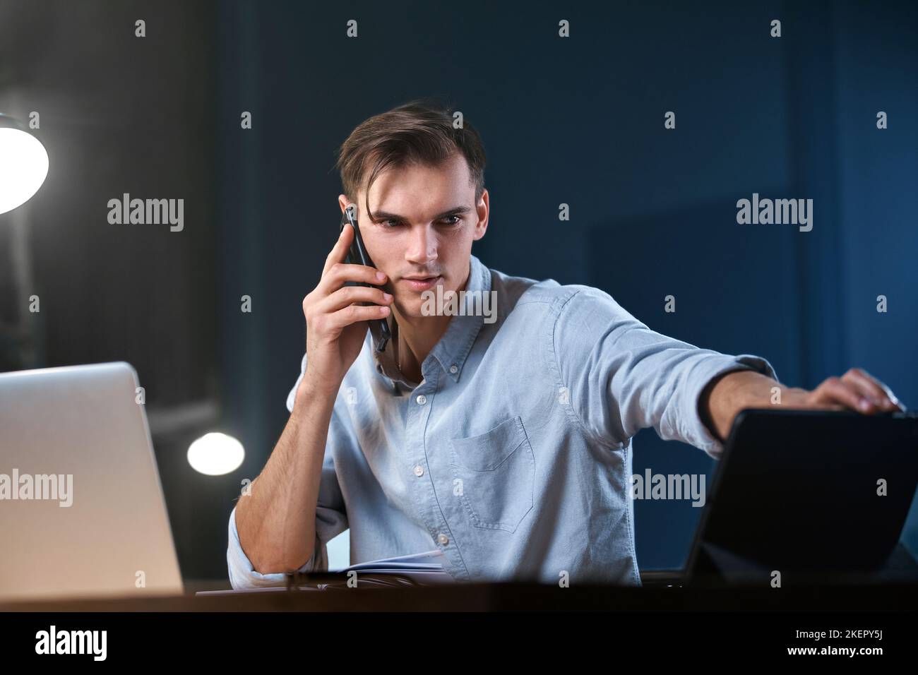 young entrepreneur talking on a smartphone while working overtime . Stock Photo
