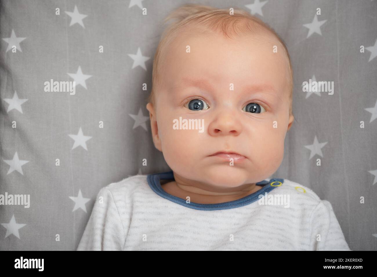 Portrait of serious newborn baby, closeup. Child with blue eyes, looking at camera. Face