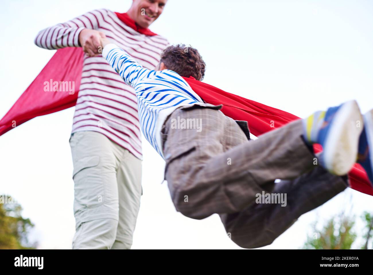 We have liftoff. a father and his young son pretending to be superheroes while playing outdoors. Stock Photo