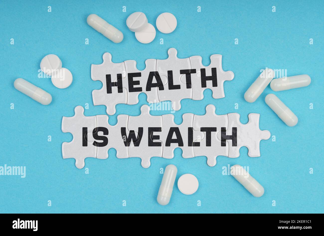 Medicine concept. On a blue background pills and puzzles with the inscription - Health Is Wealth Stock Photo