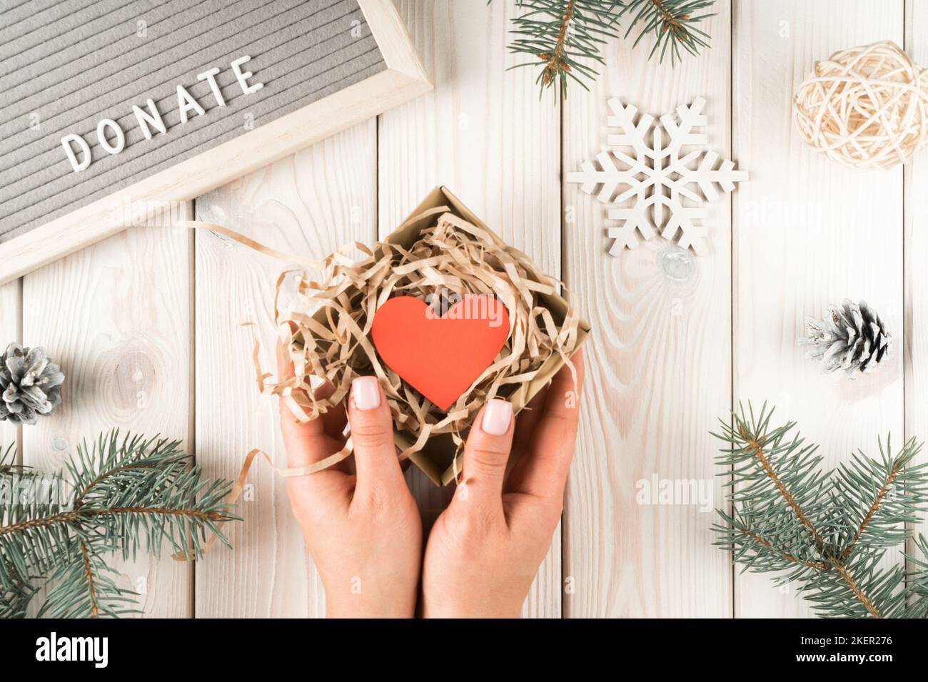 Female hands hold present donation box with red paper heart postcard