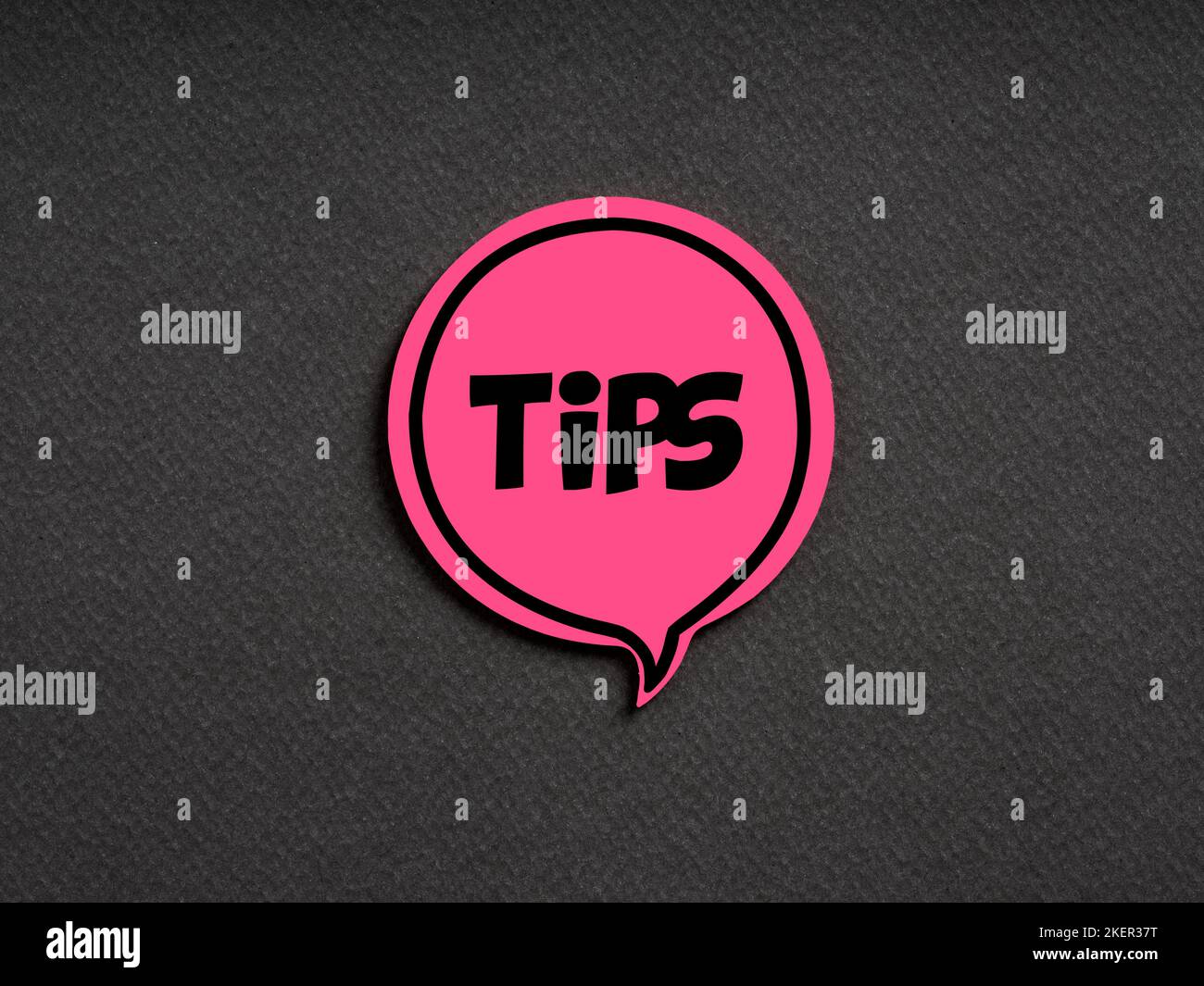 The word tips on pink speech bubble on black background. Information suggestion, advice or guidance concept. Stock Photo