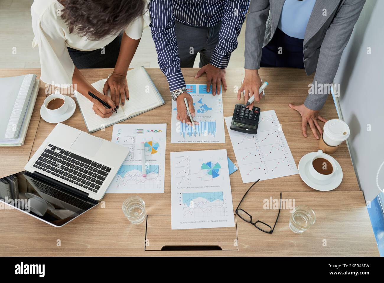 Coworkers analyzing charts and graphs at the meeting view from above