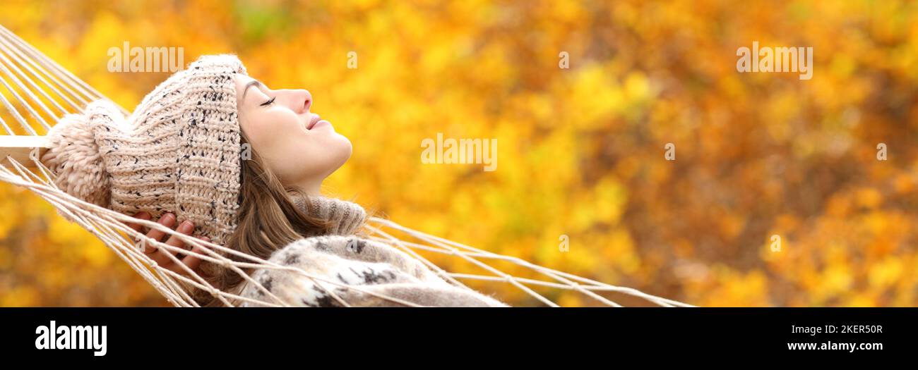 Side view banner of a woman resting in hammock in autumn holiday in a forest with orange background Stock Photo