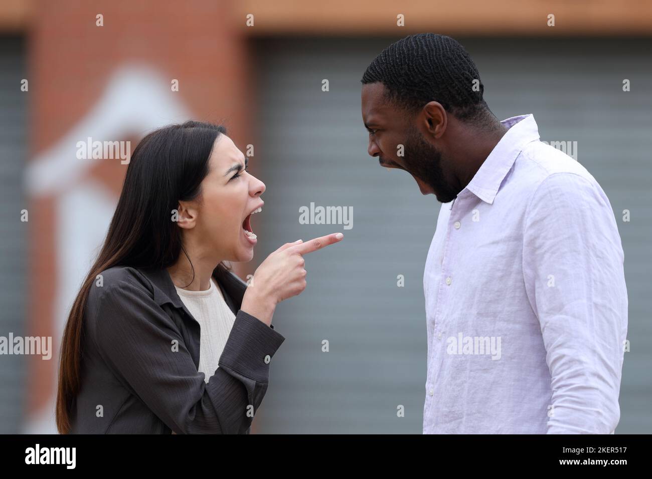 Angry woman accusing to a man shouting and arguing in the street Stock Photo