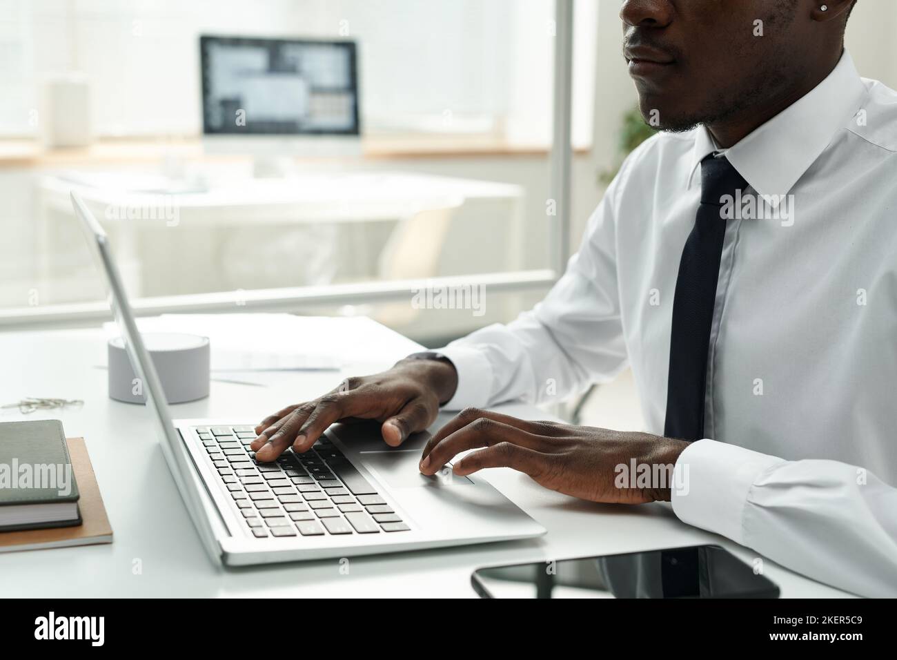 Close-up of African American businessman in white shirt working online on laptop at office Stock Photo