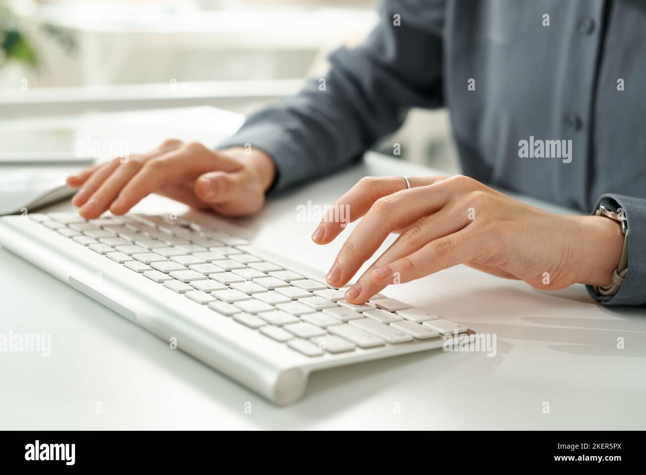 Close-up of young businesswoman typing on computer keyboard while sitting at table at office Stock Photo