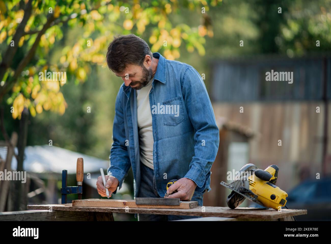Handyman measuring a board, outside in garden Stock Photo Alamy