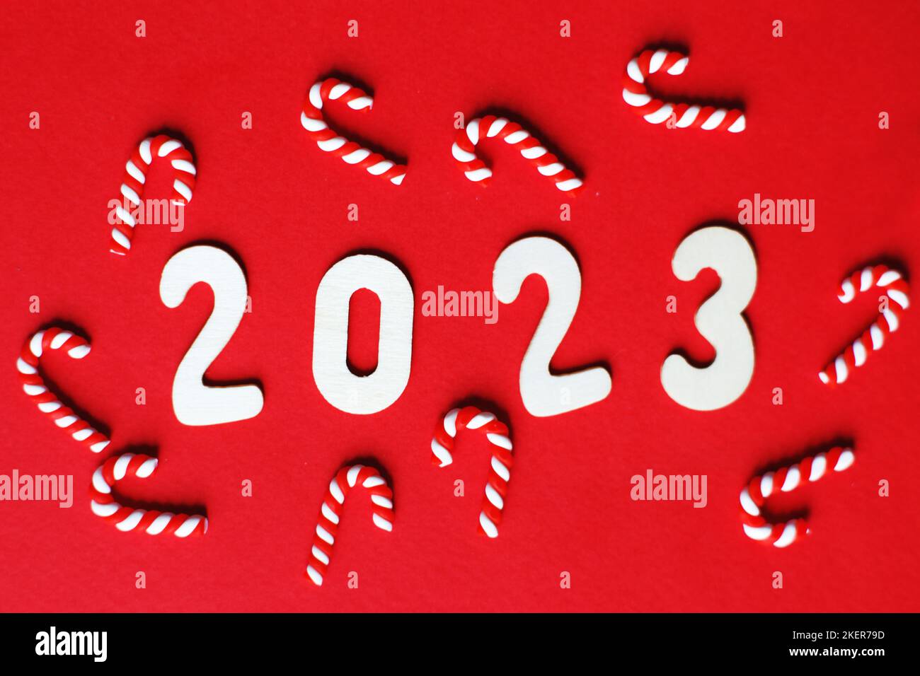 Flat lay Christmas composition with frame of candy canes and number 2023 on a red background. Copy space for text. Stock Photo