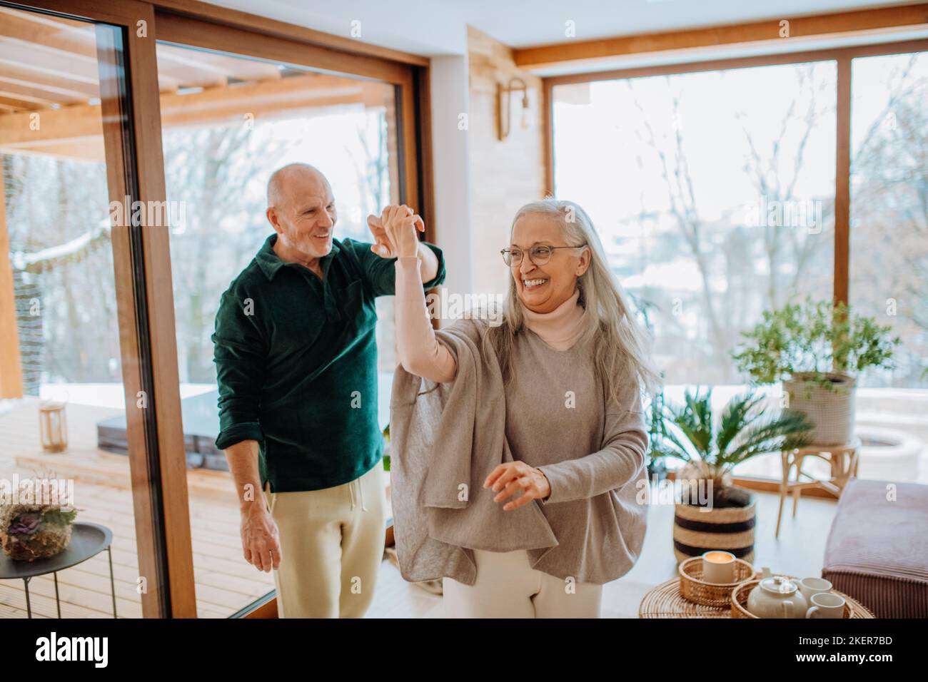 Senior couple in love dancing together in their modern living room. Stock Photo
