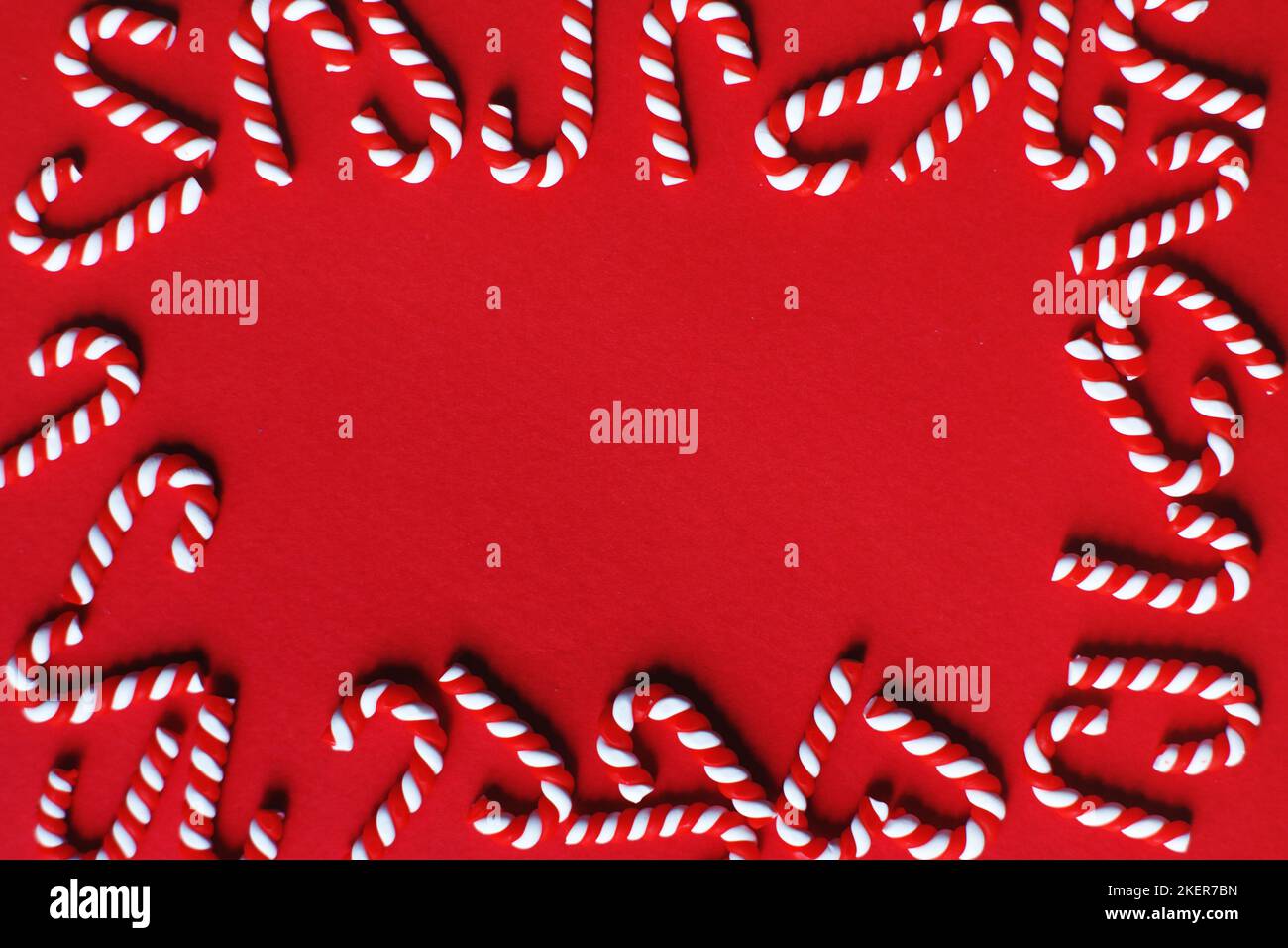 Flat lay Christmas composition with frame of candy canes on a red background. Copy space for text. Stock Photo
