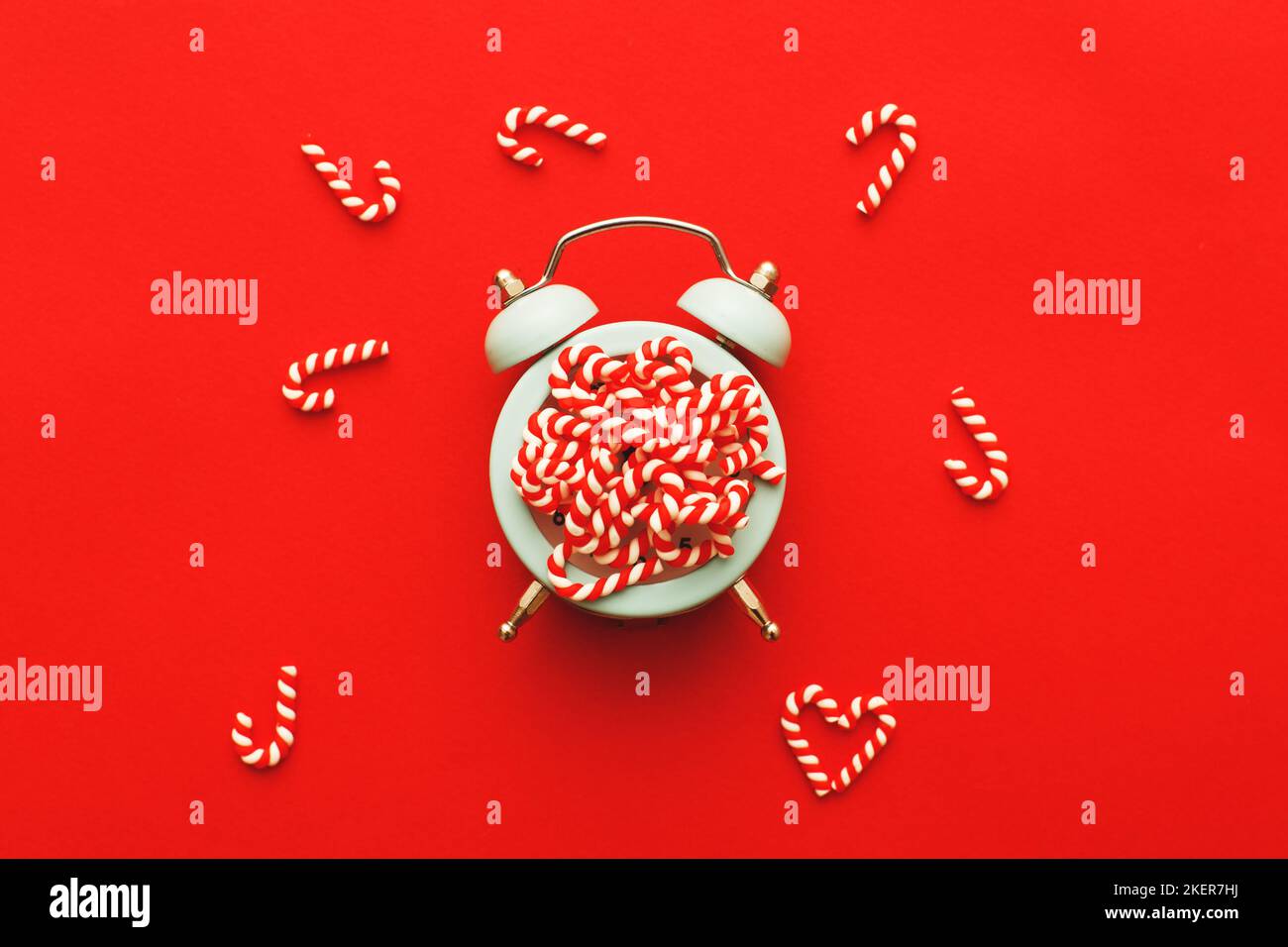 Christmas background with candy canes with the alarm clock on blue red background. Stock Photo