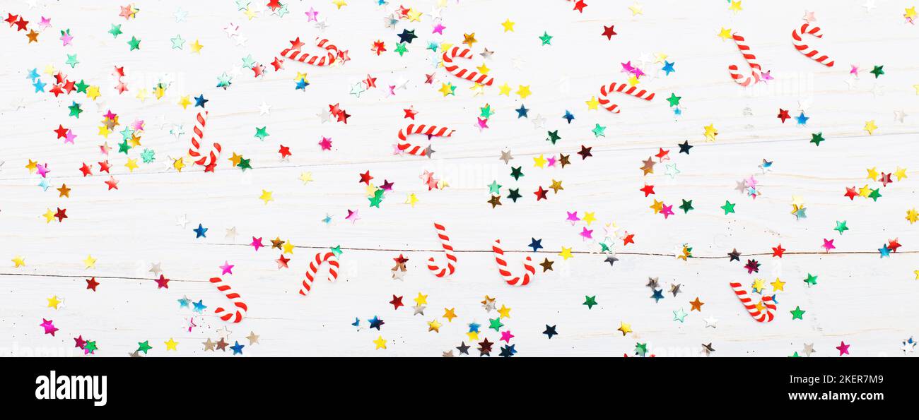Christmas background with candy canes and multicolored sequins on blue wooden background. Stock Photo
