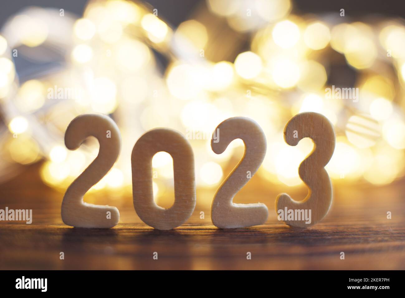 wooden number 2023 onchristmas beautifull shiny gold background. sparkle festive blurred bokeh. Stock Photo