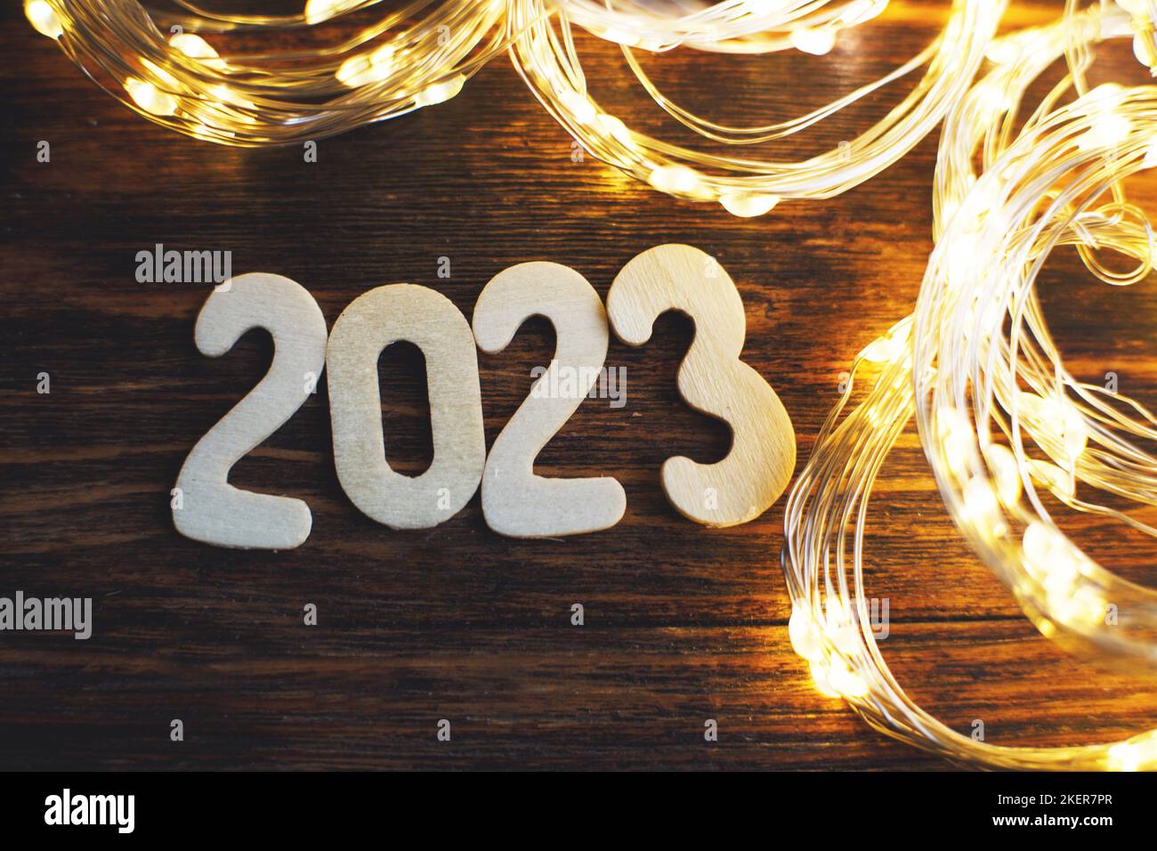 wooden number 2023 on christmas shiny wooden background. with sparkle festive gold garland. Stock Photo