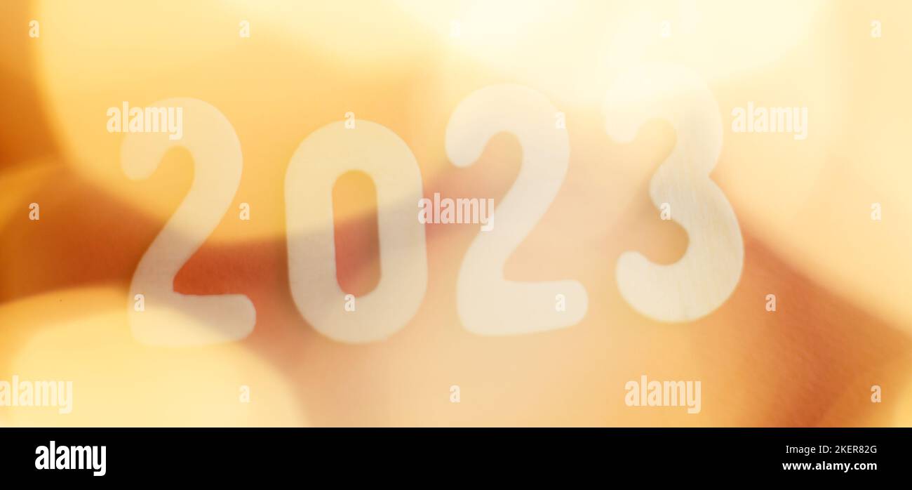 wooden number 2023 on christmas beautifull shiny gold background. sparkle festive blurred bokeh. Stock Photo