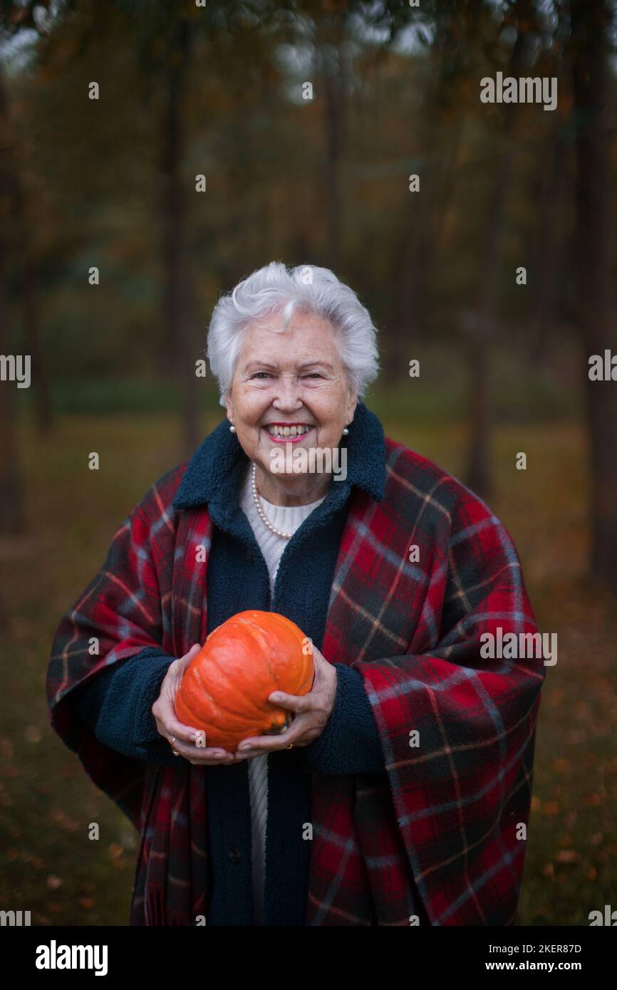 Senior woman with pumpkins in autumn forest. Stock Photo