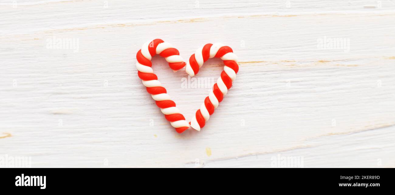 Flat lay Christmas composition with candy canes in the form oh heart on a light blue wooden background. Stock Photo