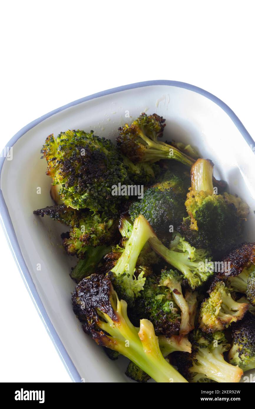 broccoli, oven roasted in olive oil,  in an enamel dish bowl. Isolated on a white background Stock Photo