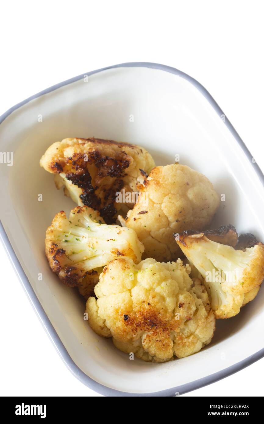 Cauliflower, oven roasted in olive oil,  in an enamel dish bowl. Isolated on a white background Stock Photo