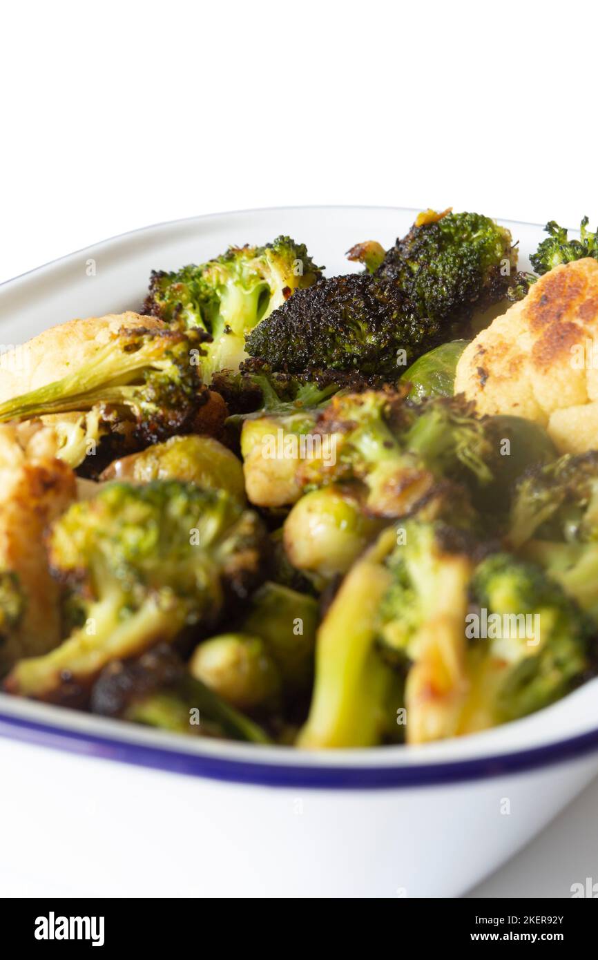 Brussels sprouts, cauliflower and broccoli, oven roasted in olive oil,  in an enamel dish bowl. Isolated on a white background Stock Photo