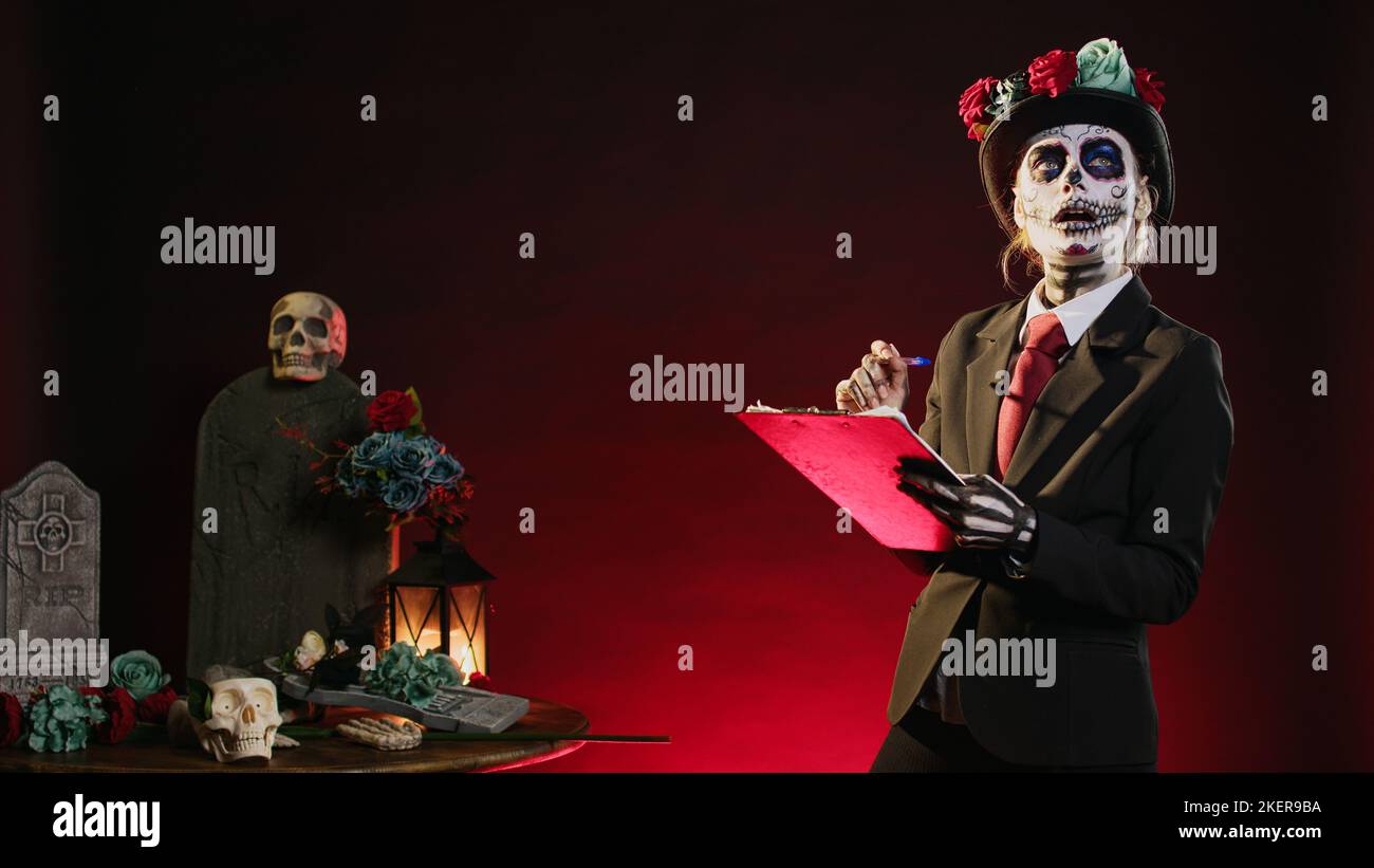 Dios de los muertos model taking notes on papers, looking like santa