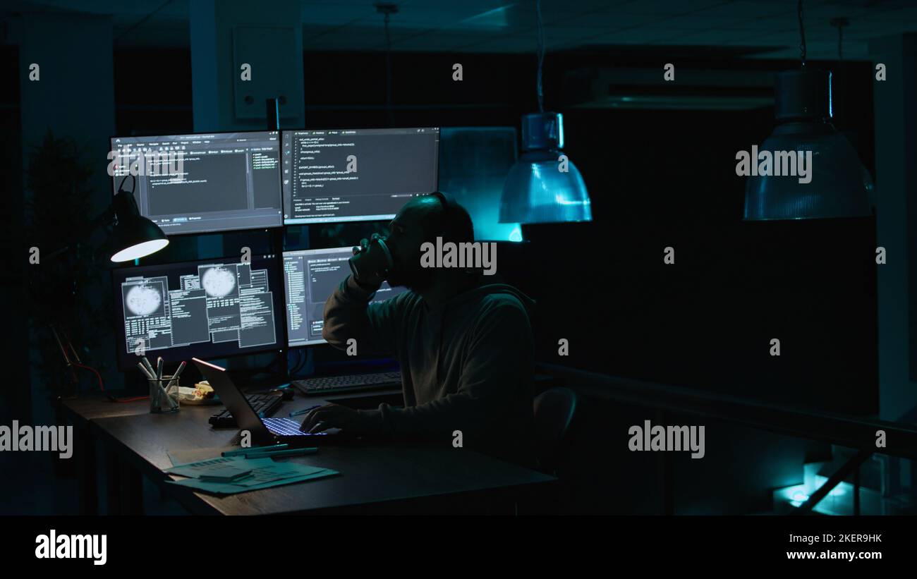 Young IT coder yawning and working on new interface, feeling sleepy late at night. Tired software engineer typing database information to create security system, being exhausted. Handheld shot. Stock Photo