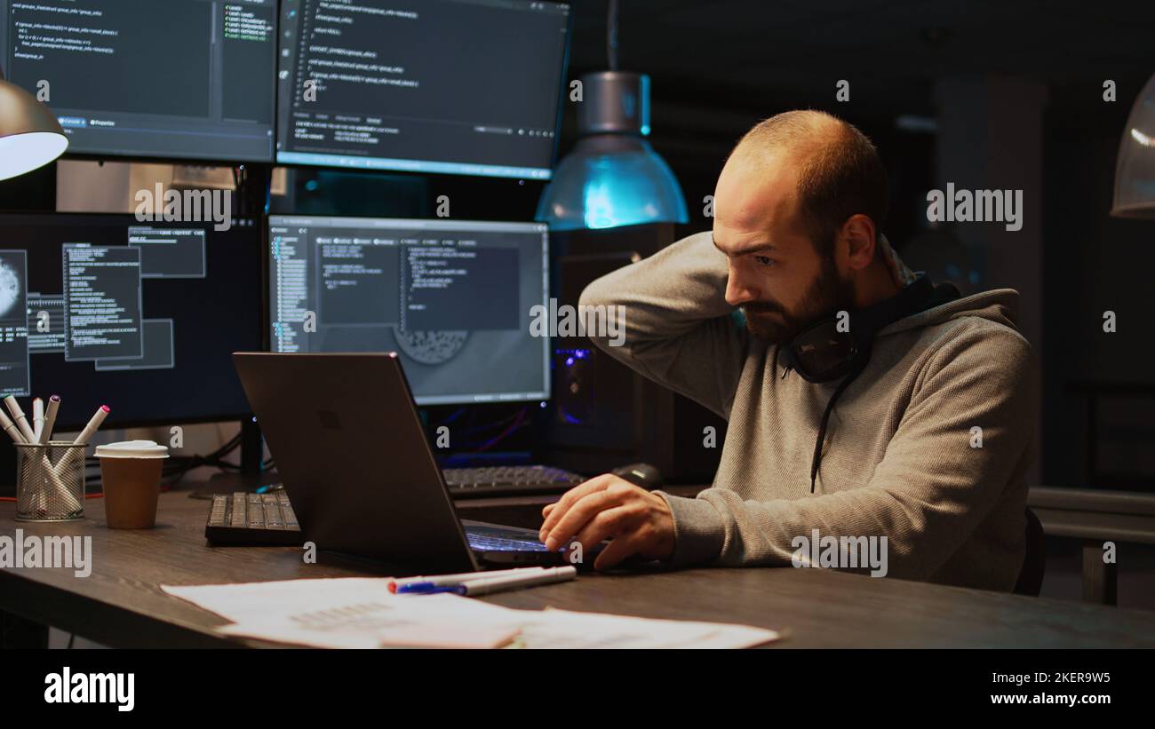 Database programer writing code and dealing with back pain, sitting at office and feeling spinal discomfort at night. App developer computing big data and coding html script on terminal window. Stock Photo