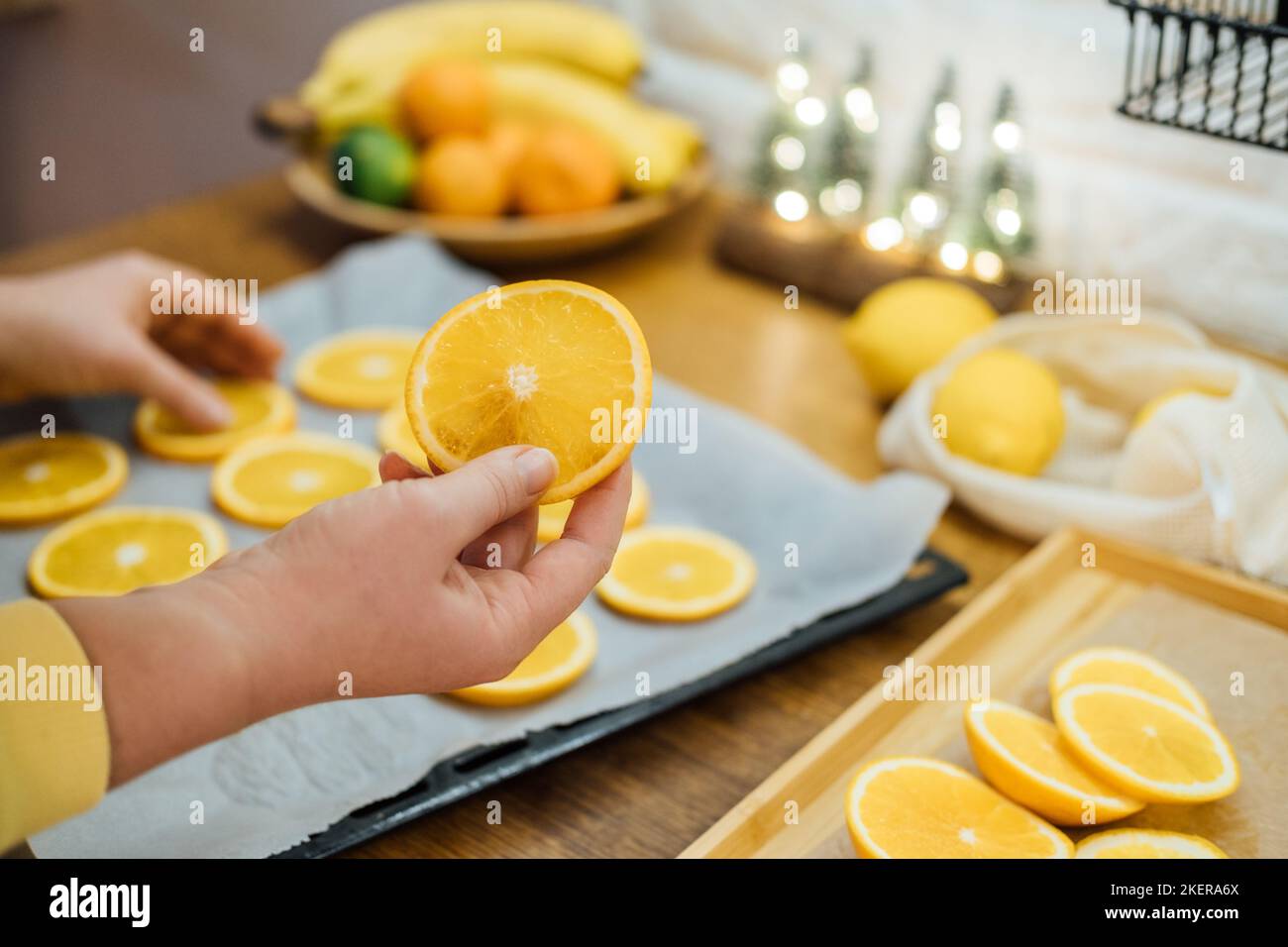 How to Dry Orange Slices for Eco friendly zero waste Holiday Decor. Close up Process of Drying Orange Slices in Oven. Woman cutting slices of orange Stock Photo